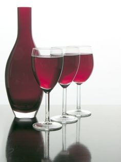 three wine glasses and a bottle on a table