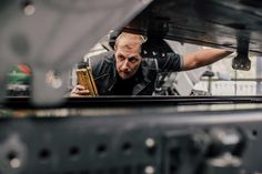 a man is looking at something in the engine compartment while working on a car's undercarriage