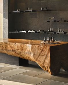 a large wooden table sitting on top of a tiled floor next to a shelf filled with knives