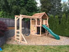 a wooden playset with a green slide and climbing frame in the back yard area