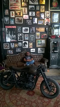 a man sitting on a motorcycle in front of a wall full of pictures and memorabilia