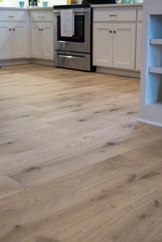 a kitchen with white cabinets and wood floors