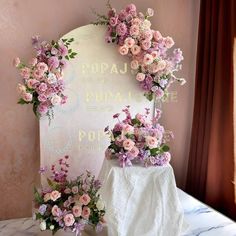 two vases filled with flowers sitting on top of a table next to a sign