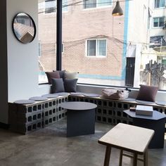 a room that has some couches and tables in front of a window with large windows