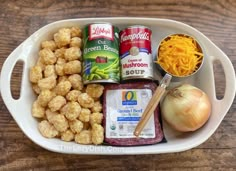 an assortment of food items in a white dish on a wooden table top with cheese, onion, and other foodstuffs