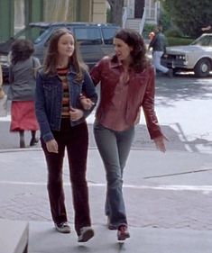 two women walking down the street talking to each other and one is holding her hand out