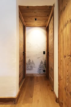 an empty hallway with wood paneling and wallpaper on the walls, leading to another room