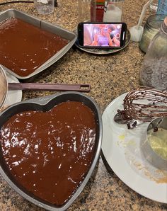 two heart shaped pans filled with chocolate on top of a counter next to a cell phone