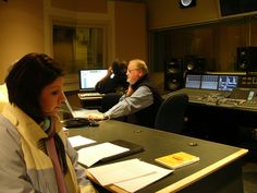 a woman sitting at a desk with headphones on in front of sound mixing equipment