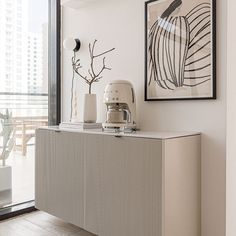 a kitchen area with an art piece on the wall and a coffee maker sitting on top of it