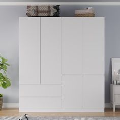 a living room with white furniture and a potted plant on top of the cabinet