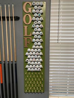 a rack with golf balls on it in front of a window next to cues and cues