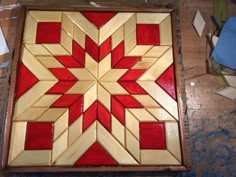 a red and white wooden art piece sitting on top of a table next to a pair of scissors