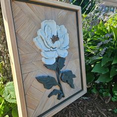 a white flower sitting on top of a wooden frame