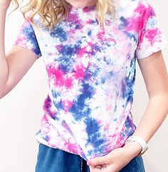 a woman with blonde hair wearing a tie dye t - shirt and blue denim shorts