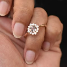 a woman's hand holding a ring with an oval shaped diamond in the center