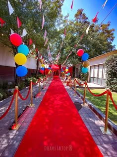 a red carpeted walkway with balloons and streamers on the sides, leading to a building