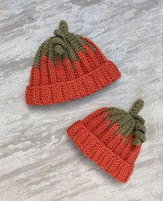 two crocheted hats sitting on top of snow covered ground next to each other