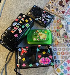 several small cameras sitting on top of a table next to each other with stickers all over them