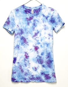 a blue and purple tie - dyed shirt hanging on a clothes hanger against a white wall