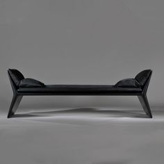 a black bench sitting on top of a white floor next to a gray wall with no one in it