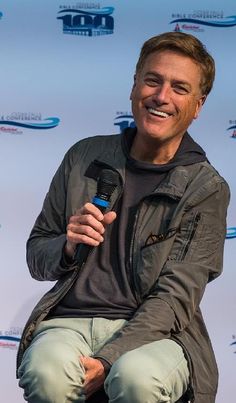 a man sitting on top of a chair holding a microphone