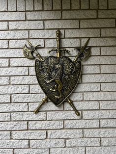 a wall with a metal shield and two crossed swords on it, in front of a brick wall