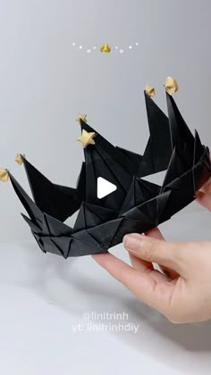 a hand holding a black origami crown