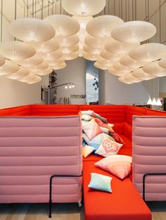 a red couch with pillows on it and some lights hanging from the ceiling