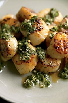 scallops with pesto and parsley on a white plate