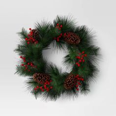 a christmas wreath with pine cones and red berries on white background, ready to be hung