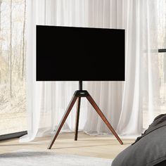 a flat screen tv sitting on top of a tripod in front of a window