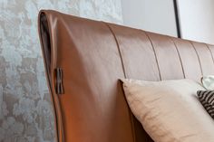 a brown leather headboard with several pillows on it