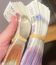 the person is holding two bundles of money in their hand, both with different colors