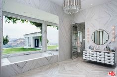 a bathroom with marble walls and flooring next to a large window that looks out onto the outdoors