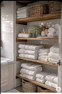 the shelves are filled with white towels and other items in baskets on top of them