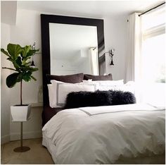 a bedroom with a bed, mirror and potted plant