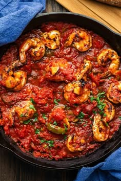 shrimp and tomato sauce in a cast iron skillet on a wooden table with bread