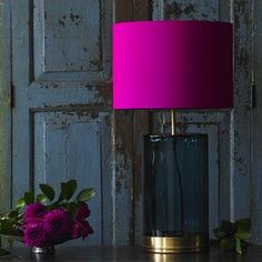 a purple lamp sitting on top of a table next to a vase filled with flowers