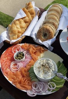 an assortment of food is displayed on a table with breads and dips in bowls