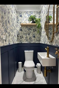 a bathroom with blue and white wallpaper, gold fixtures and a toilet in the corner