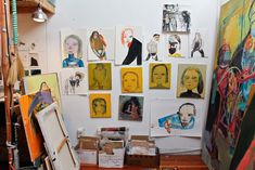 an artist's studio with many paintings and drawings on the wall, including portraits