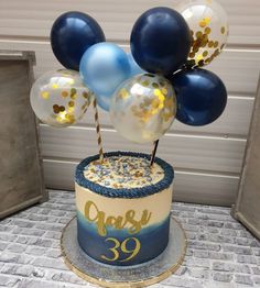 a birthday cake with blue and gold balloons