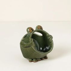 a green ceramic frog planter sitting on top of a white table