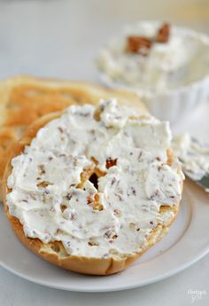 a bagel with white frosting and walnuts on it sitting on a plate