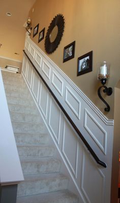 an image of a hallway with pictures on the wall and stairs leading up to it