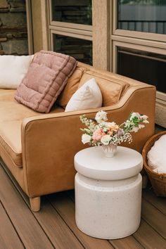 a couch sitting on top of a wooden floor next to a basket filled with flowers