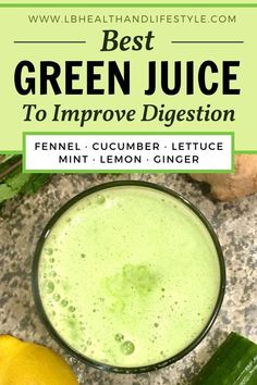 a glass filled with green juice next to lemons and cucumbers