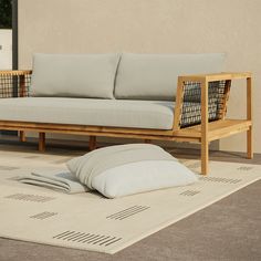 a couch sitting on top of a white rug next to a wooden frame and pillow