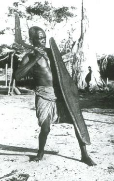 an old photo of a man holding a surfboard